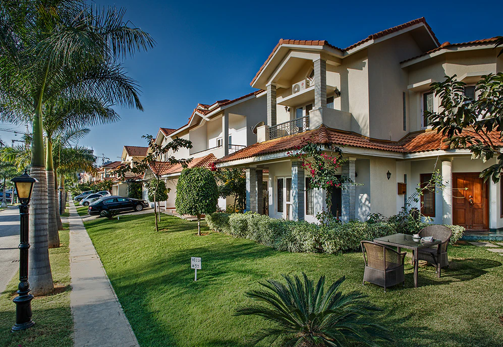White villas with red-tiled roofs, private gardens and internal walkways at Adarsh Palm Retreat in Bengaluru