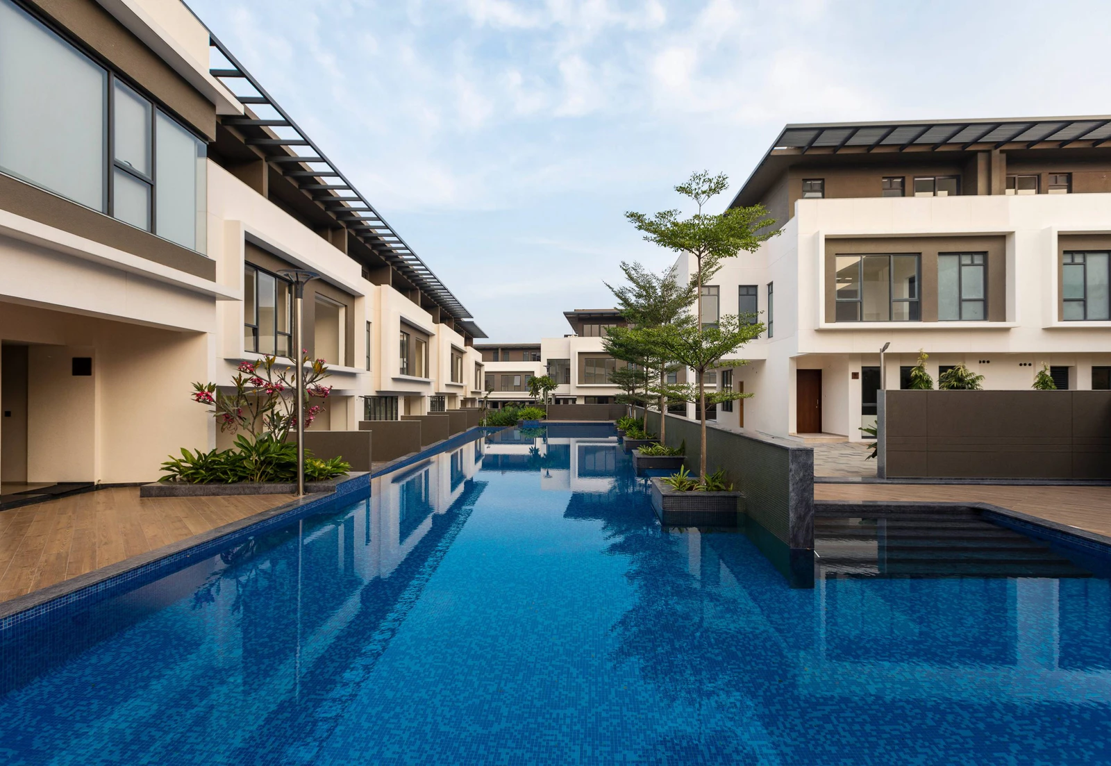 Rows of white independent villas and sheltered terraces along a shared pool courtyard at Alanoville in Bengaluru