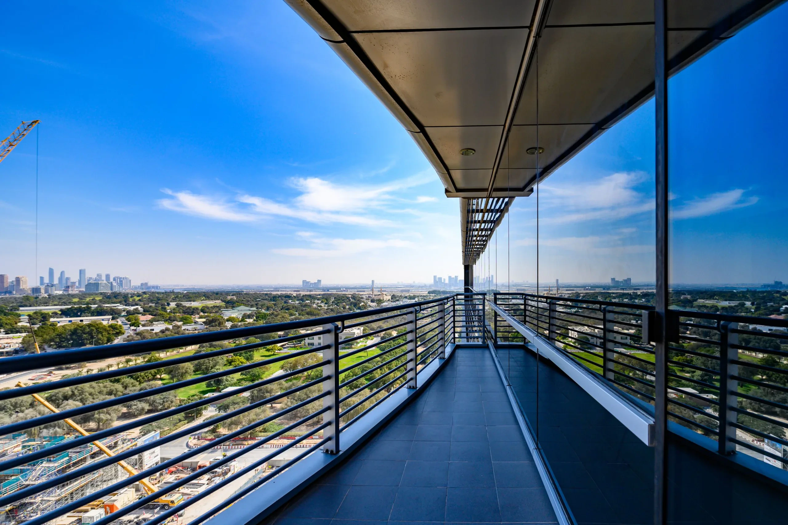 High-rise terrace with glass and steel railing overlooking a city skyline