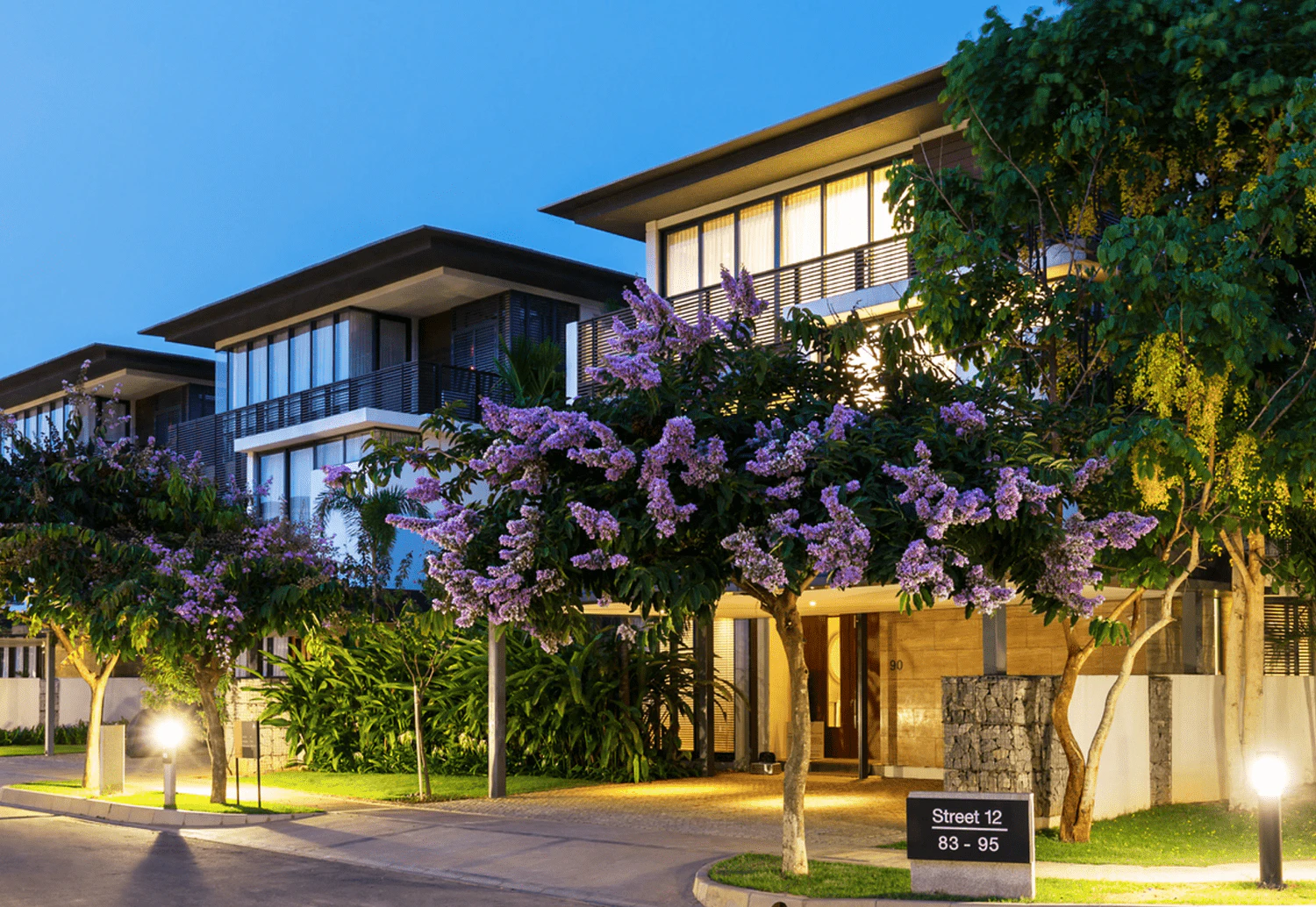 Evening photograph of a residential street and illuminated independent villas at Embassy Boulevard in Bengaluru