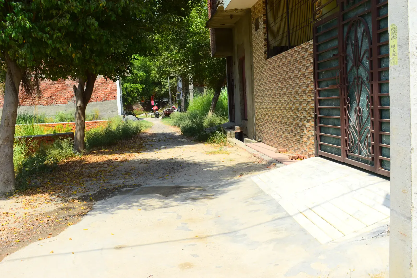 Saipuram: shaded lane beside a house with an ornate metal door