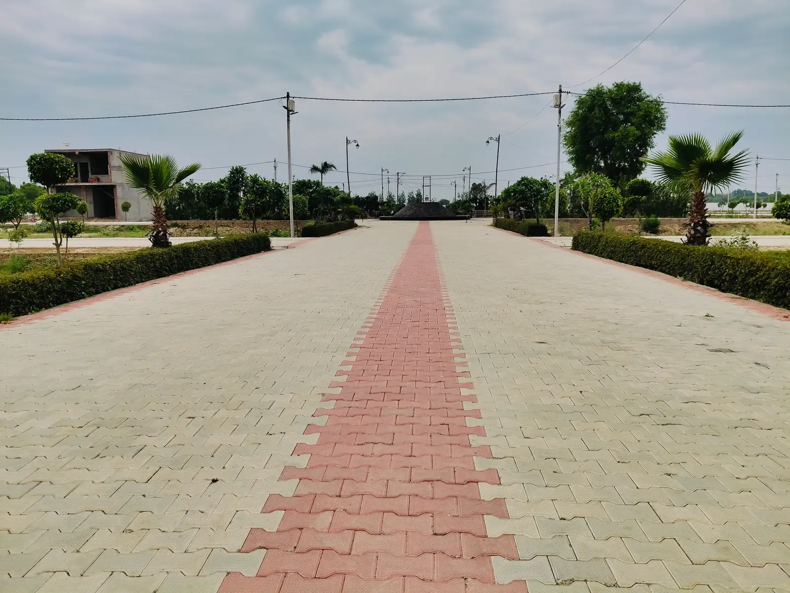 River Green Society: wide paved boulevard with a red centre stripe, clipped hedges and palms leading to the fountain