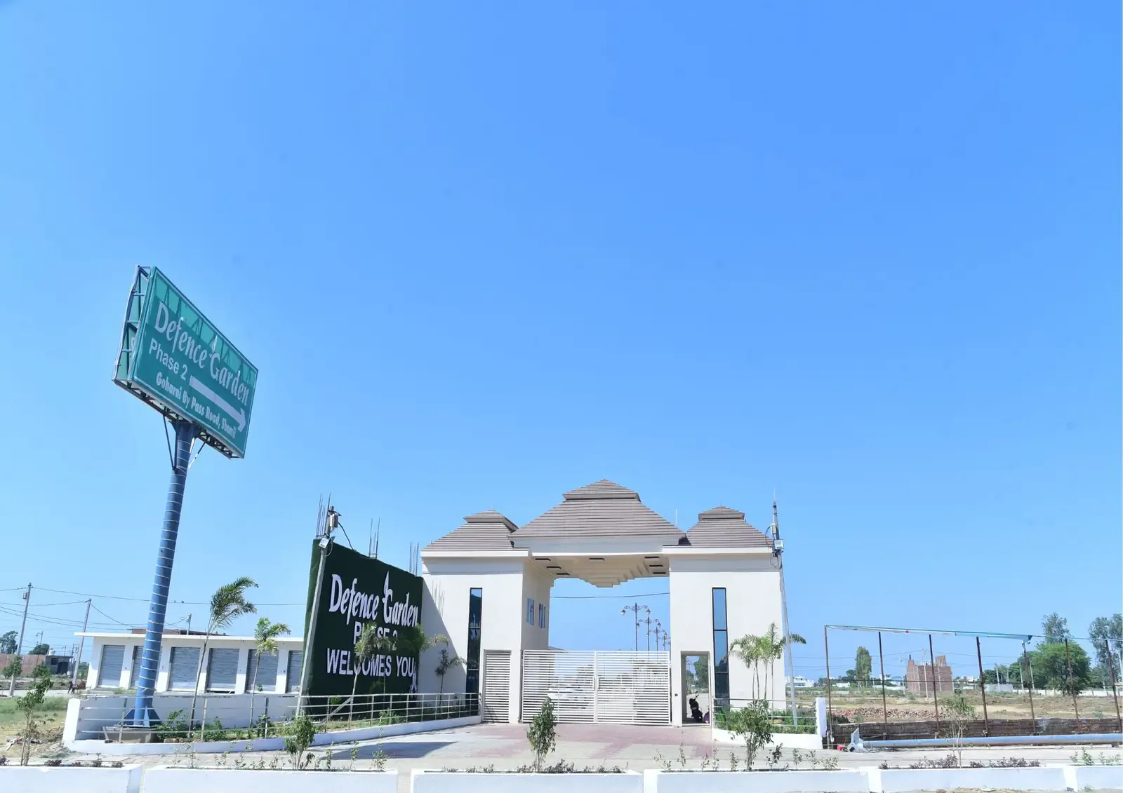 Defence Garden Phase 2 entrance and roadside billboard under a clear blue sky