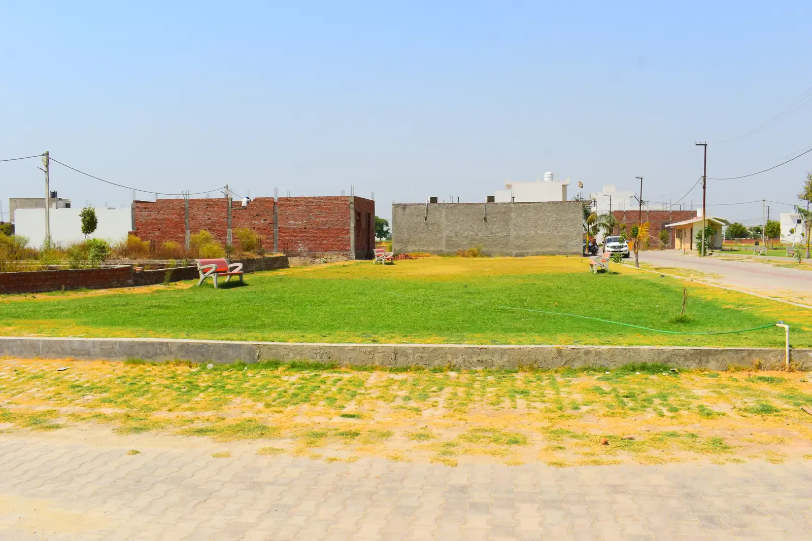 Basant Kunj: open green park with brick boundary walls beyond a paved road