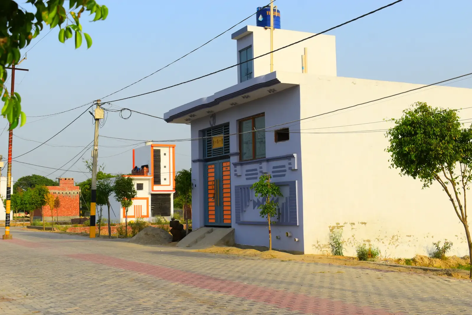 Defence Garden Budhana: lavender house on a paved street with neighbouring homes beyond