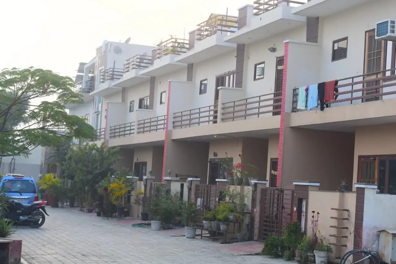Ganpati Enclave: terrace of townhouses along a paved lane lined with potted plants
