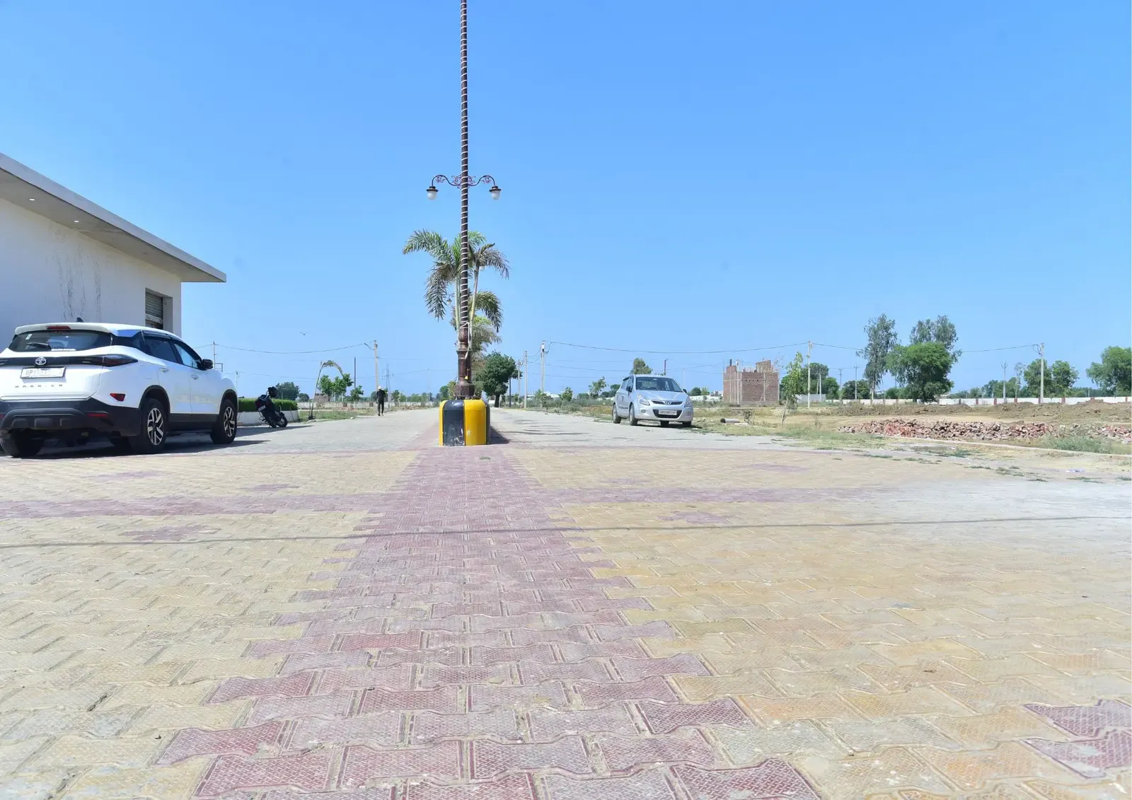 Defence Garden Phase 2: broad paved boulevard with a central lamp post under a blue sky