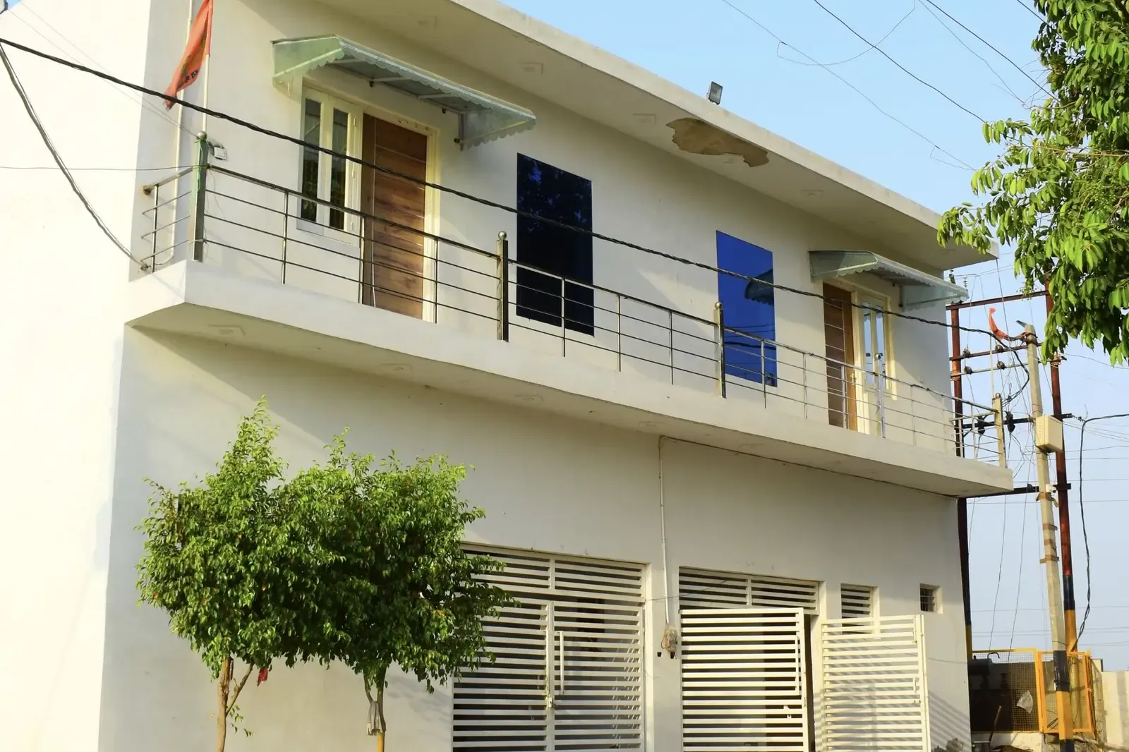 Defence Garden Budhana: two-storey white house with balcony railings and rolling shutters