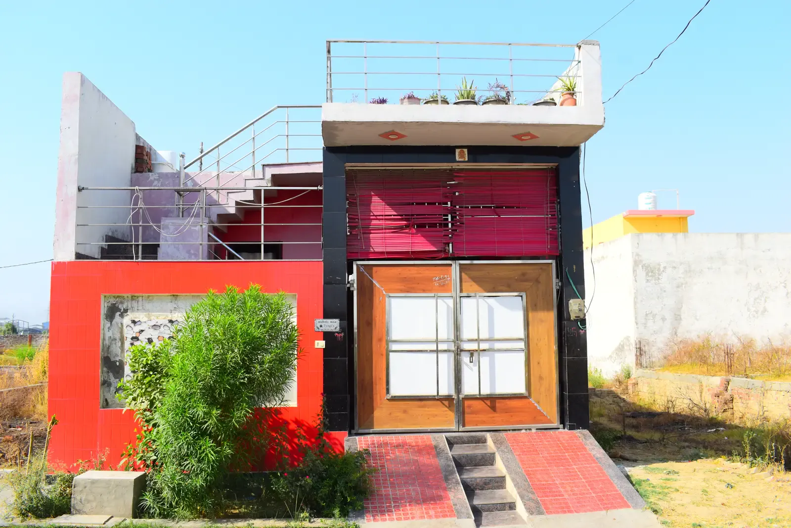 Defence Kunj: red-and-black modern house with a timber front door