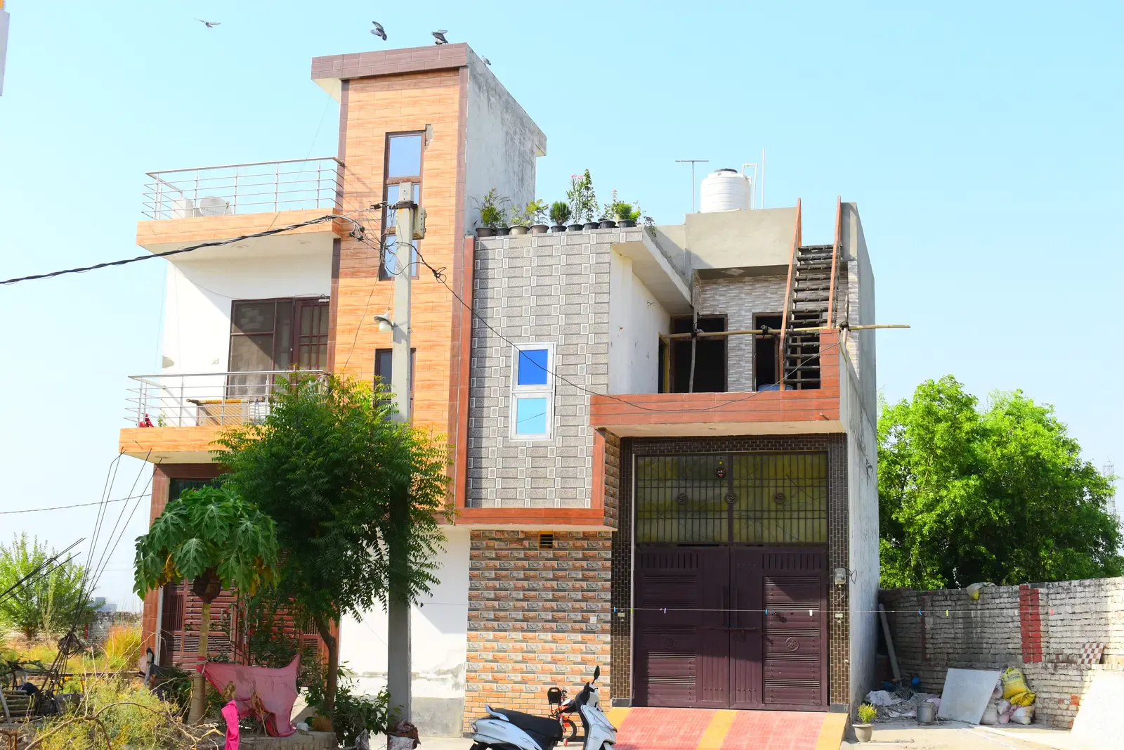 Defence Kunj: home with wood-effect and stone cladding, a scooter parked in front