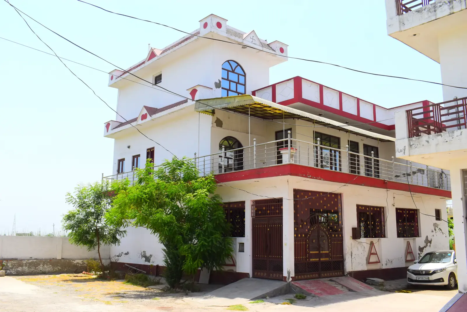 Defence Garden Meerut: three-storey white house with red trim, an arched window and balconies