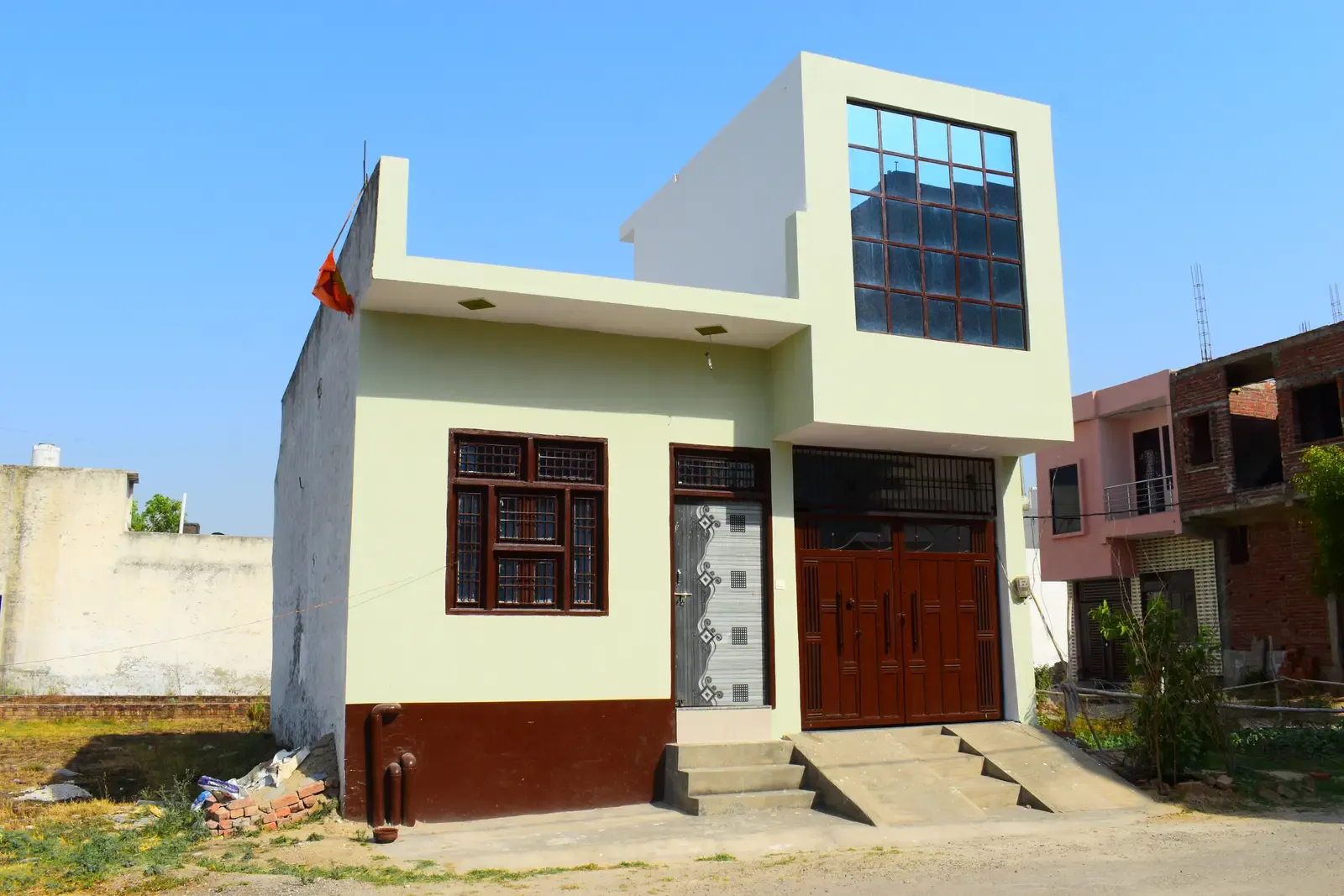 Defence Kunj: compact cream house with a glass-block window and timber doors