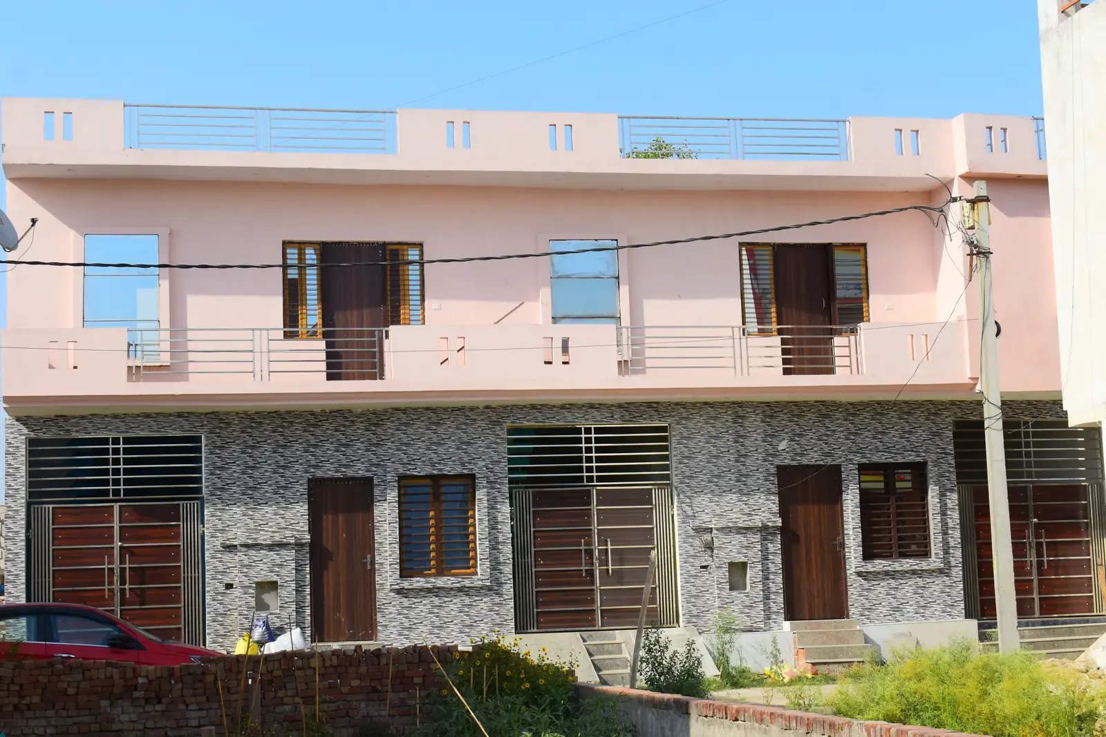 Defence Kunj: row of pink two-storey homes with stone-clad ground floors