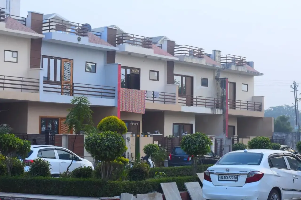 Ganpati Enclave: townhouses behind a clipped hedge, cars parked in front