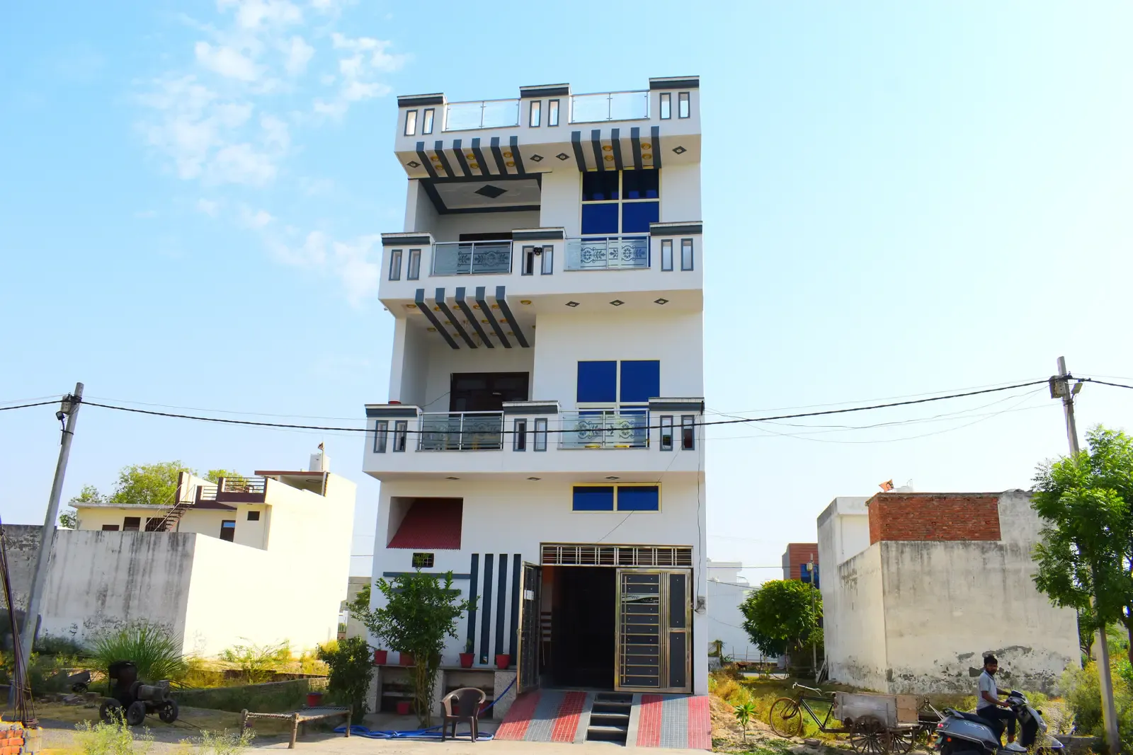 Defence Kunj: tall four-storey white home with blue windows and balconies