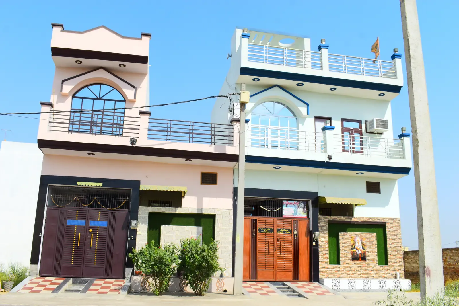Defence Kunj: two adjoining two-storey homes, one pink and one white with blue trim, with arched windows