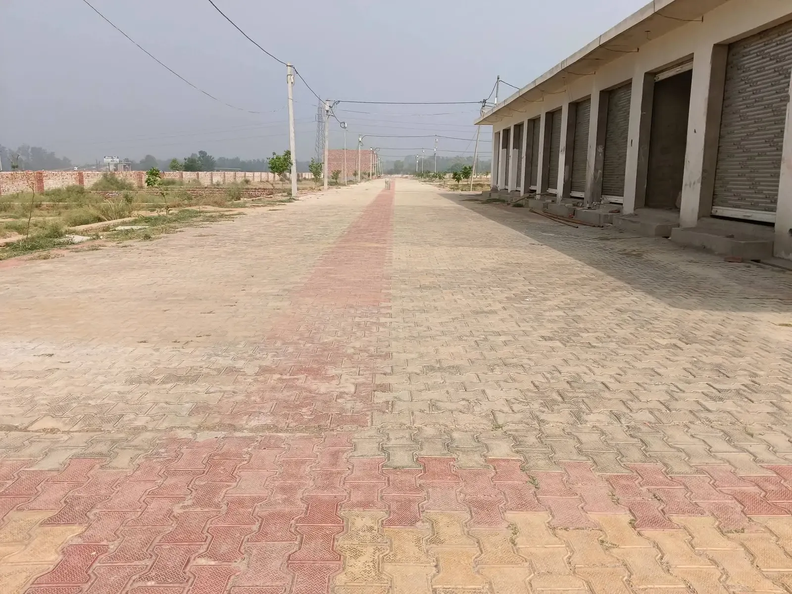 Defence Garden Phase 2: paved service road along a row of shuttered shops