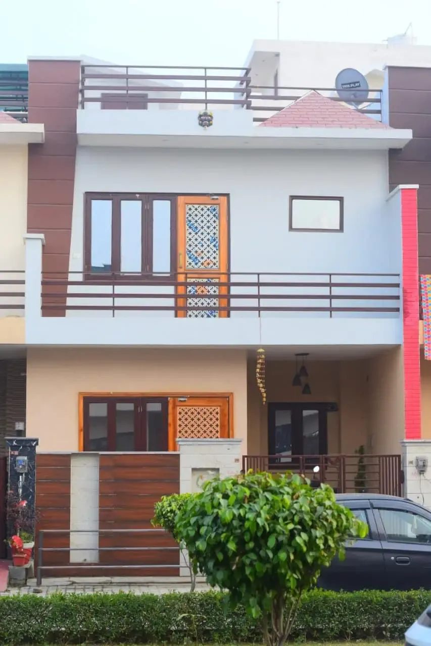 Ganpati Enclave: townhouse facade with a balcony and carved timber screen