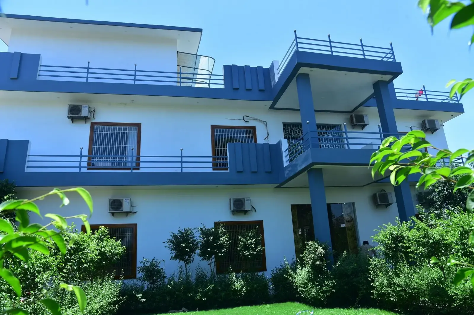 Defence Garden Phase 1: blue-and-white three-storey villa with wide balconies behind lush planting