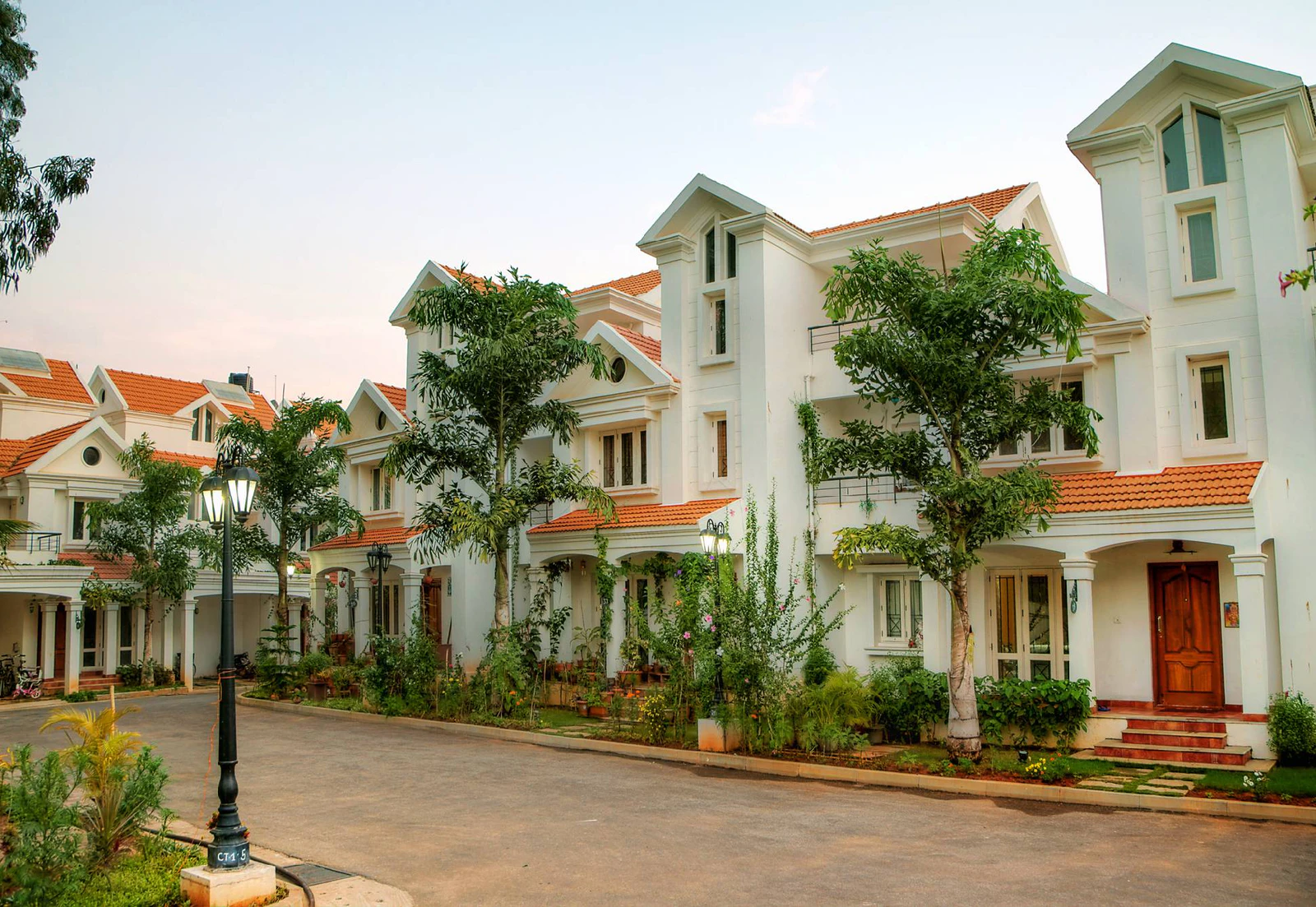 White villas with terracotta roofs along a paved residential lane at MIMS Ardendale in Bengaluru