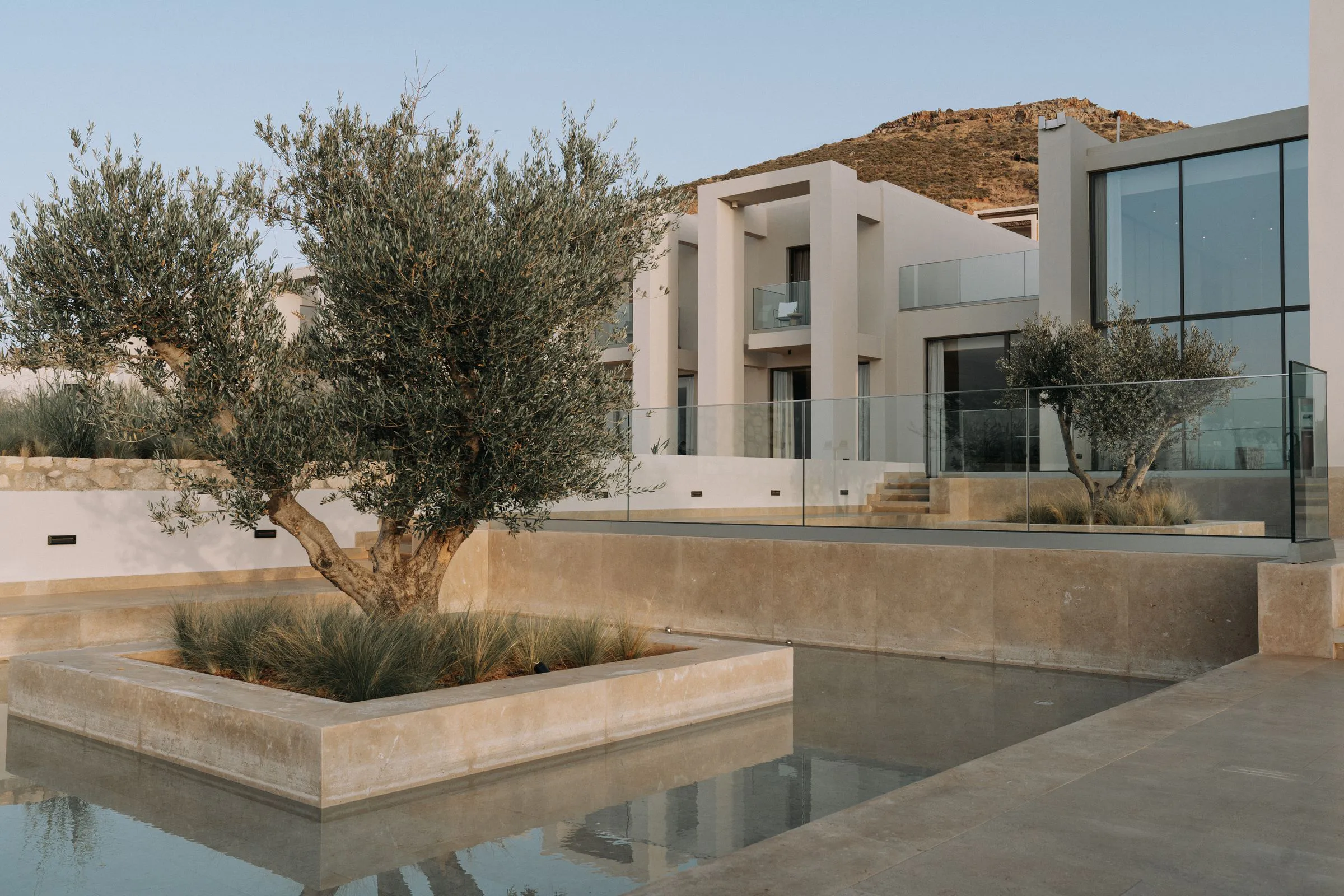 Stone courtyard and reflecting pool in front of a contemporary white residence